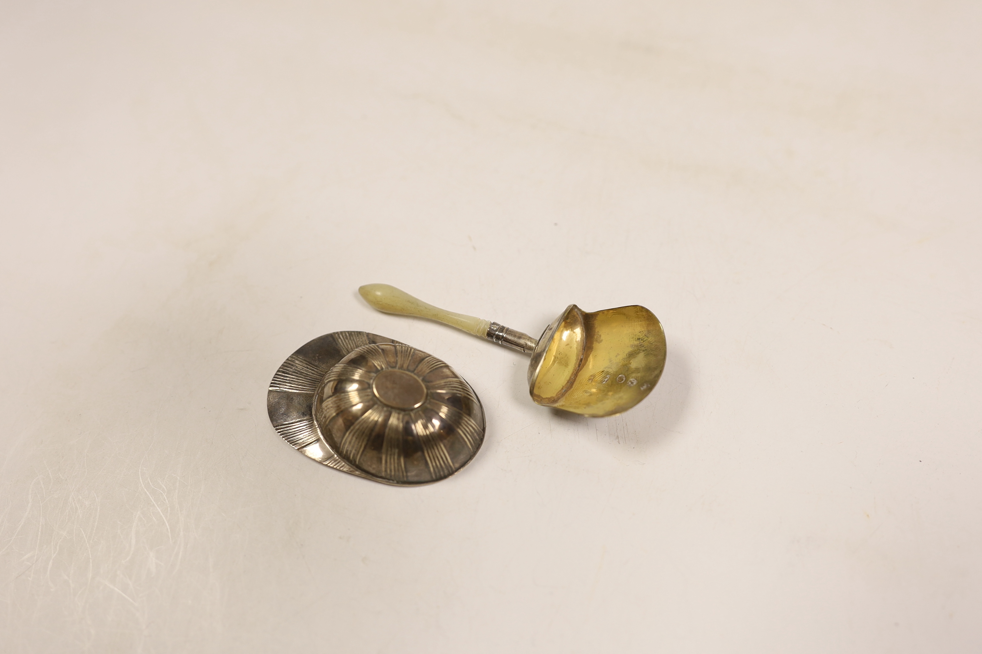 A George III silver jockey cap caddy spoon, Birmingham, 1798?, 54mm and another George III silver gilt shovel caddy spoon, with mother of pearl handle, Birmingham, 1806.